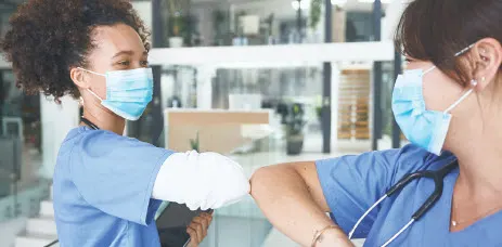 Two female doctors bumping elbows with each other