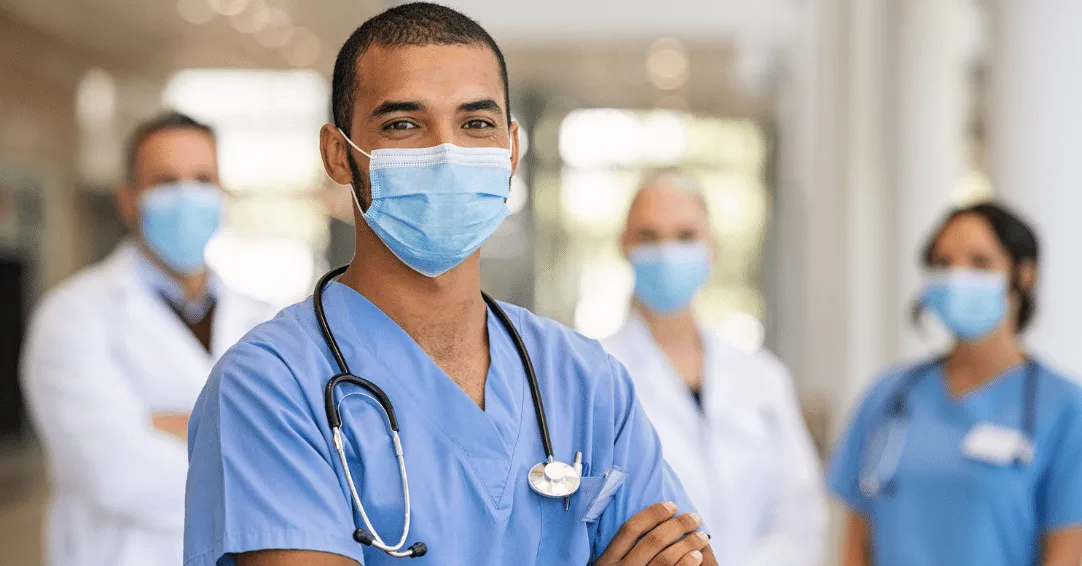 Male nurse with face mask standing in front of colleagues