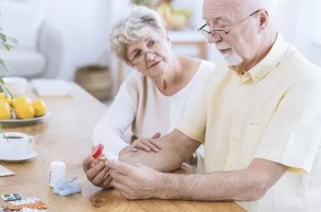 Worried wife supporting sick husband taking drugs for hypertension