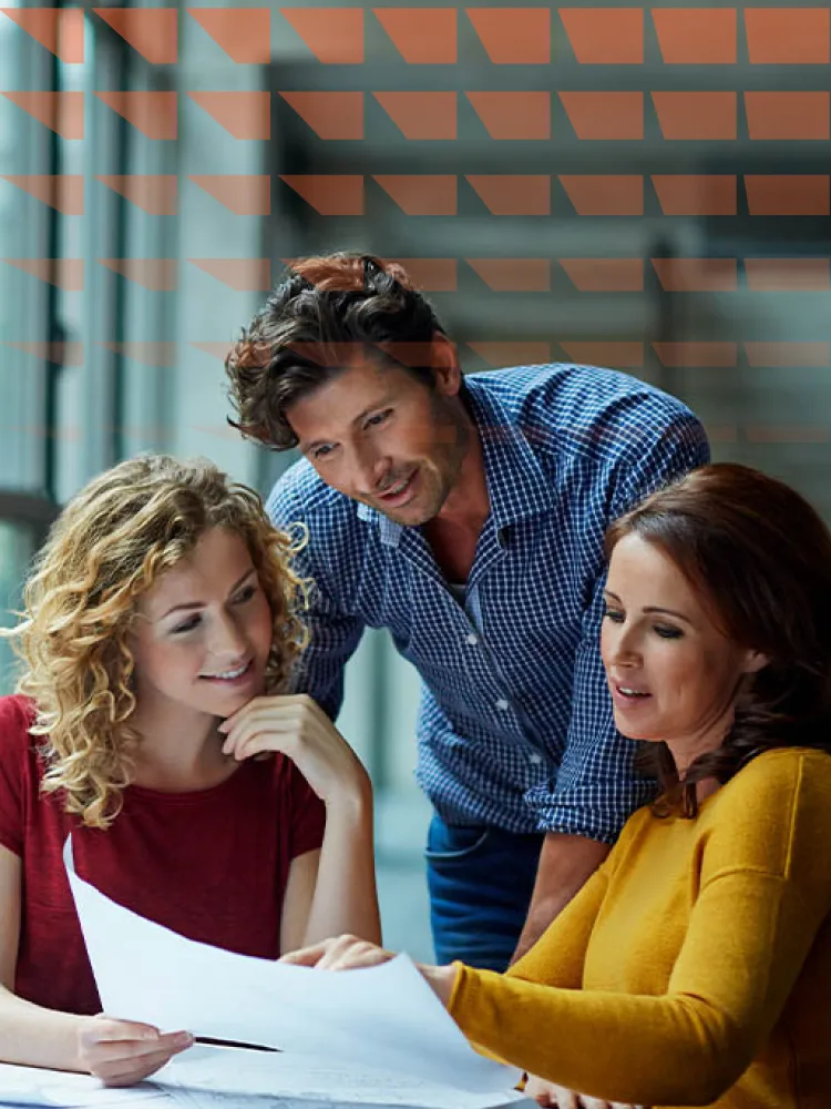 Three people standing around a table looking at a piece of paper