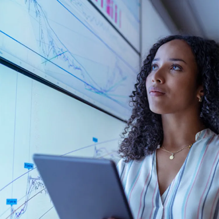 Female researcher with tablet in front of screen with analytics 