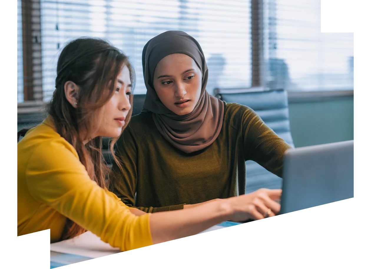 Two Asian businesswomen talking while working together with laptop in a modern office startup