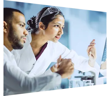 Two lab technicians collaborating on a touch-screen monitor