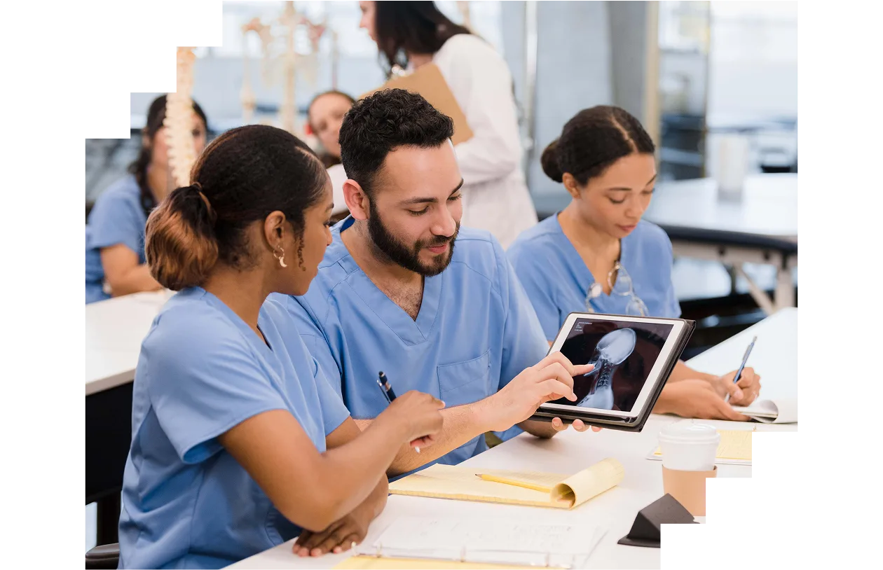Male intern explains x-ray displayed on screen to female classmate