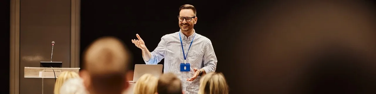A man standing up facing committee members and speaking or leading a discussion