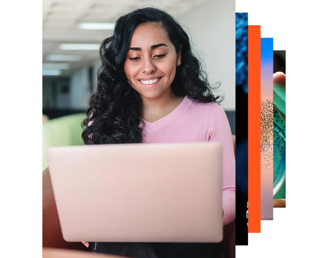 Young smiling Latin American student using a laptop to study in a college campus corridor