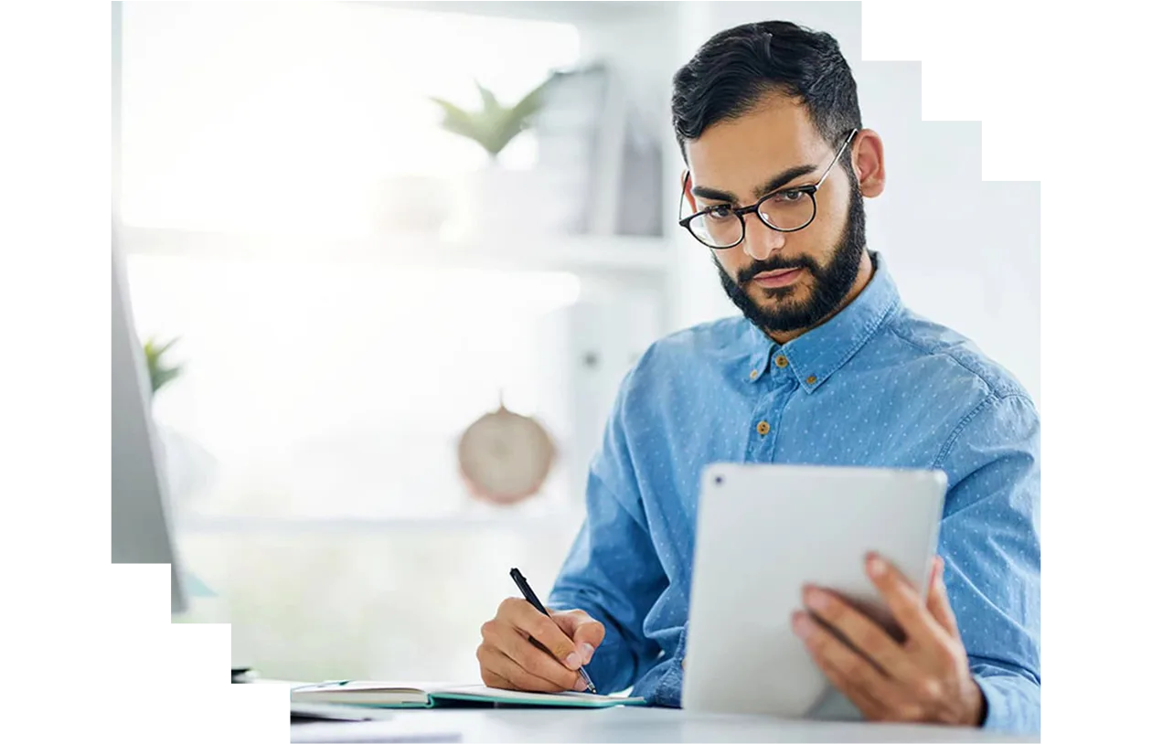Young designer using a digital tablet while writing notes in an office