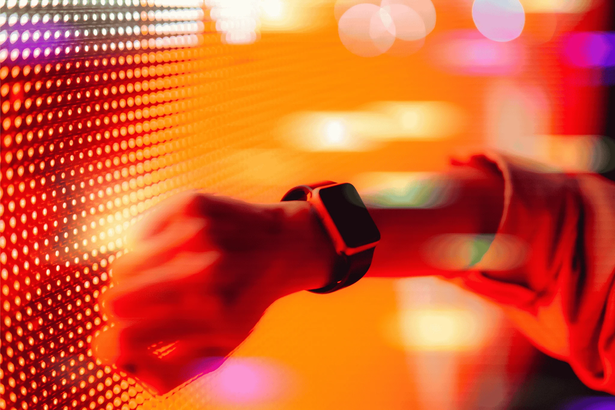 Woman using smart watch against colourful neon light display