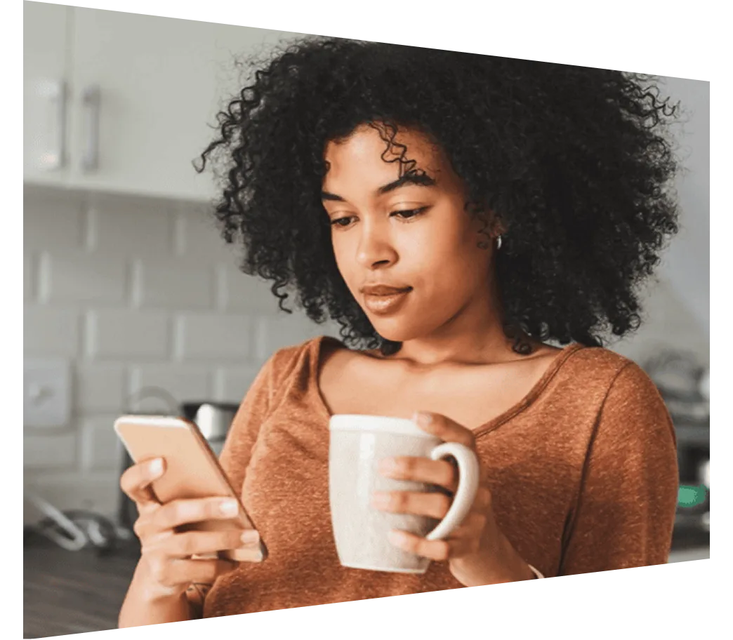 Young woman looking at phone while drinking coffee