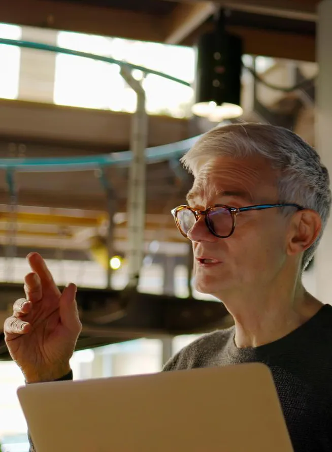 Mature man conducting a seminar / lecture with the aid of a large screen