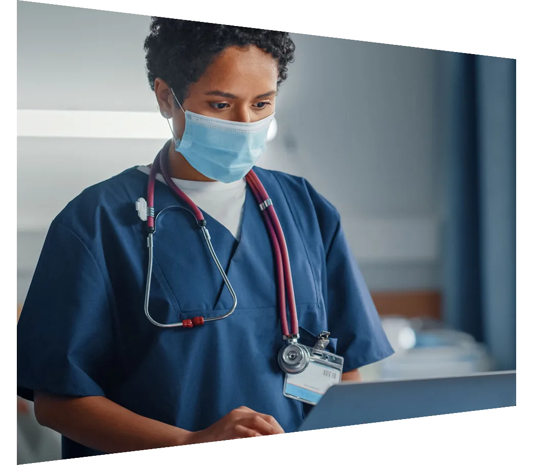 Female doctor wearing mask reviewing laptop notes