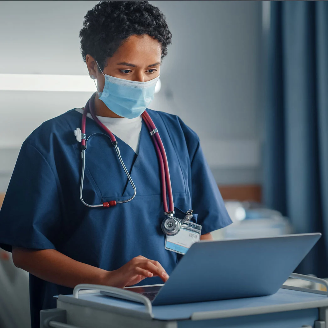 Female doctor wearing mask reviewing laptop notes