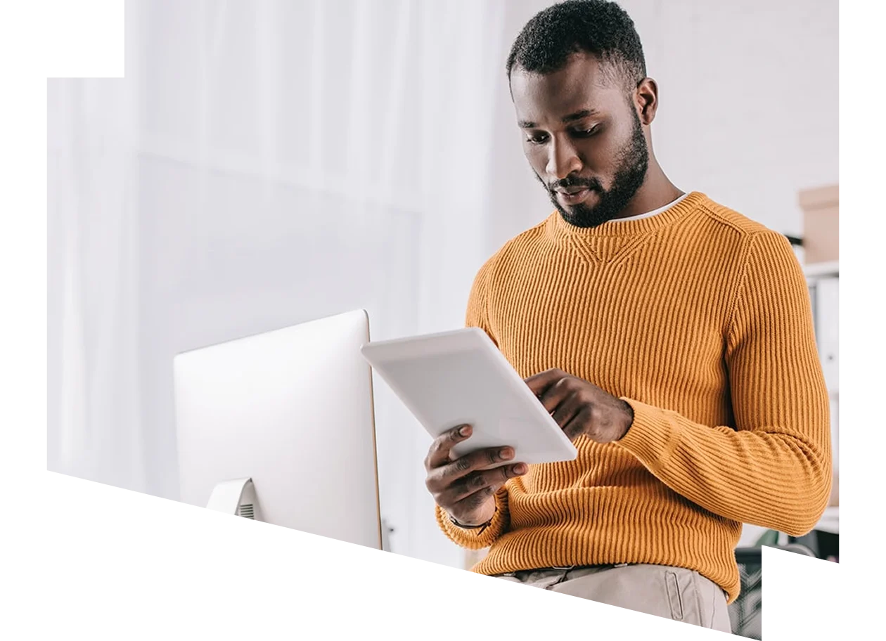 Man standing at desk and looking at iPad 