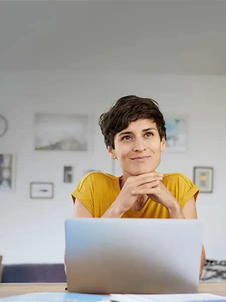 Optimistic woman in yellow shirt working on laptop in her home office