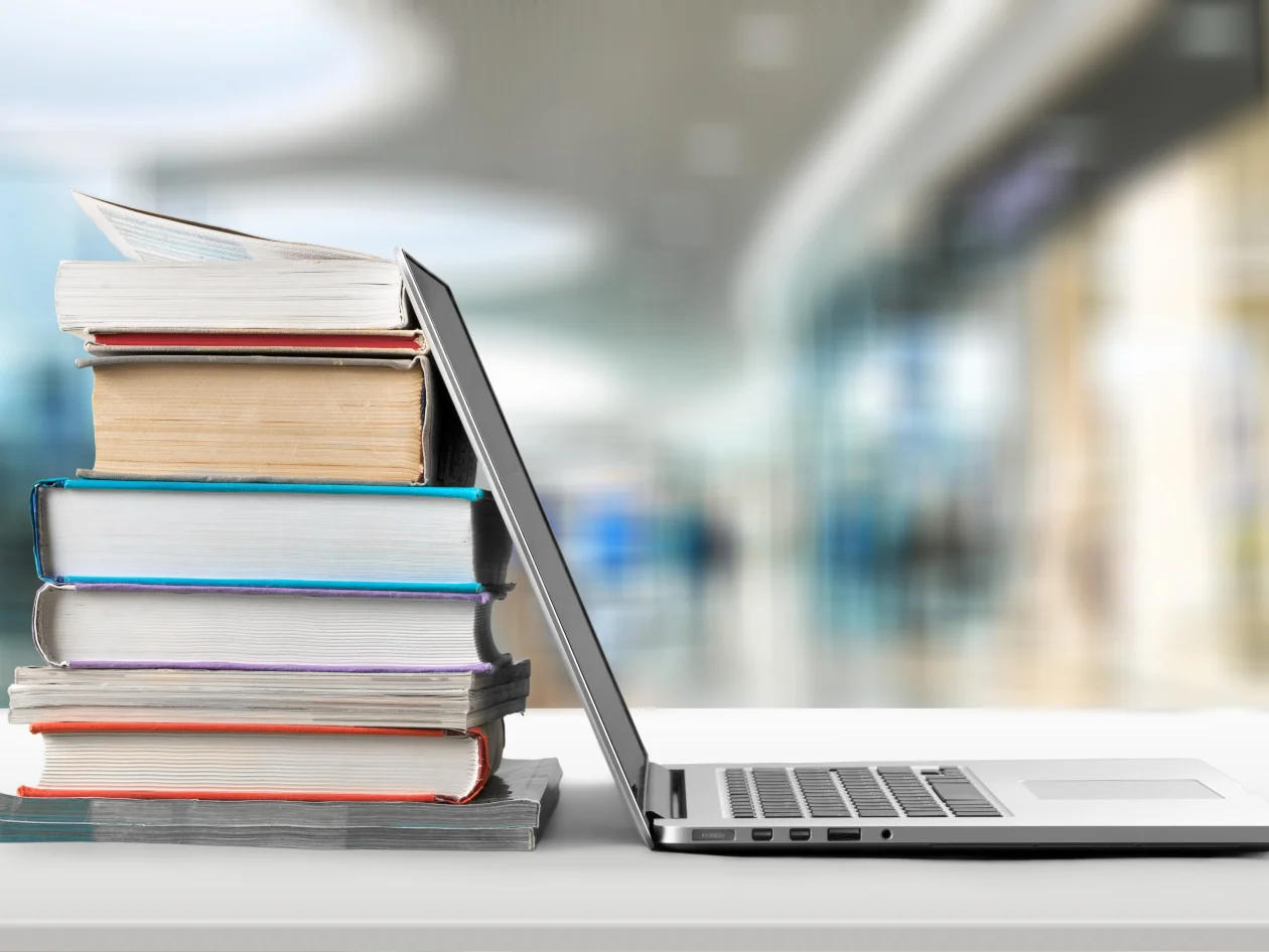 A laptop leaning against a stack of books