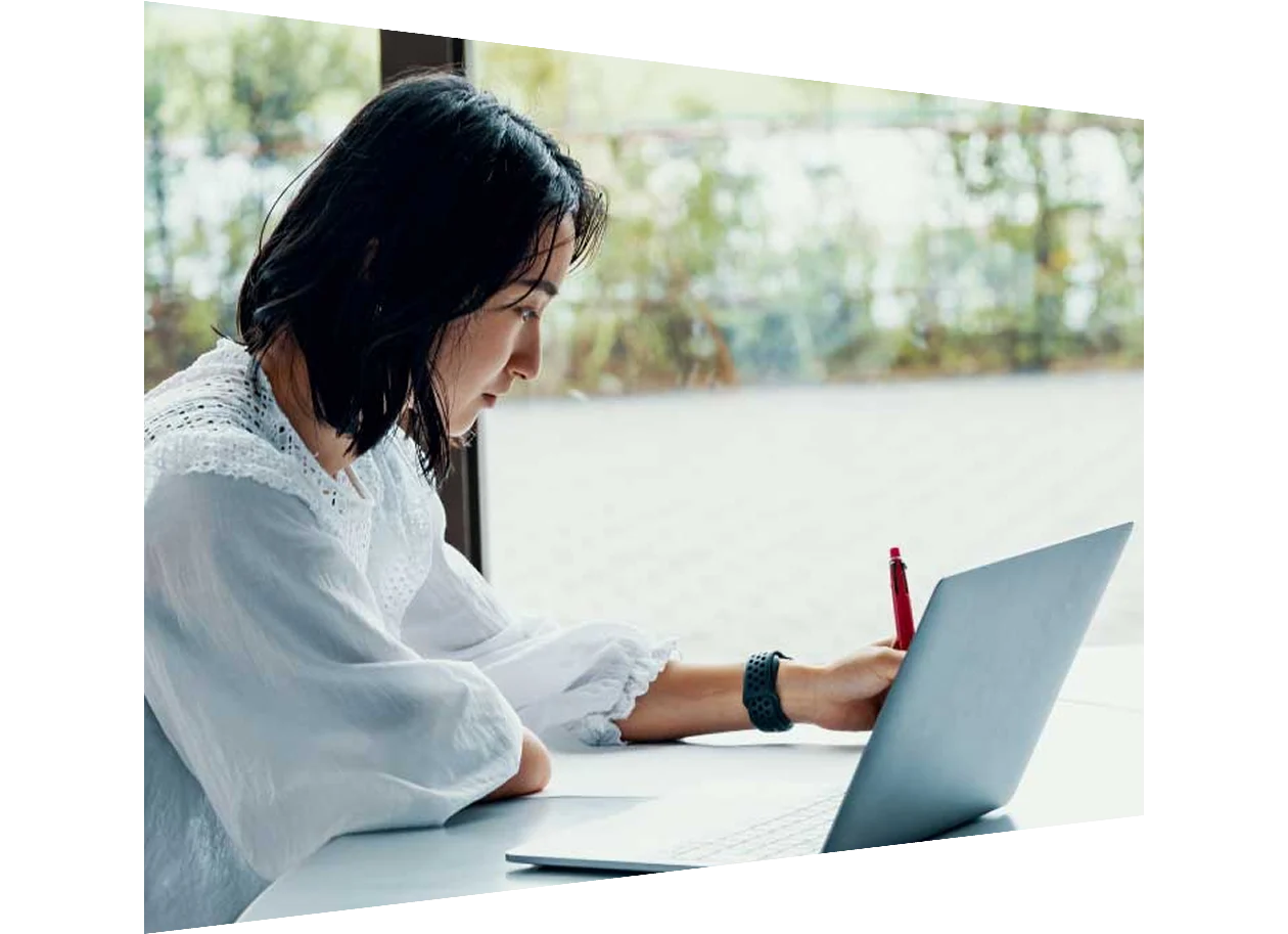 Young Asian student looking at laptop and taking notes