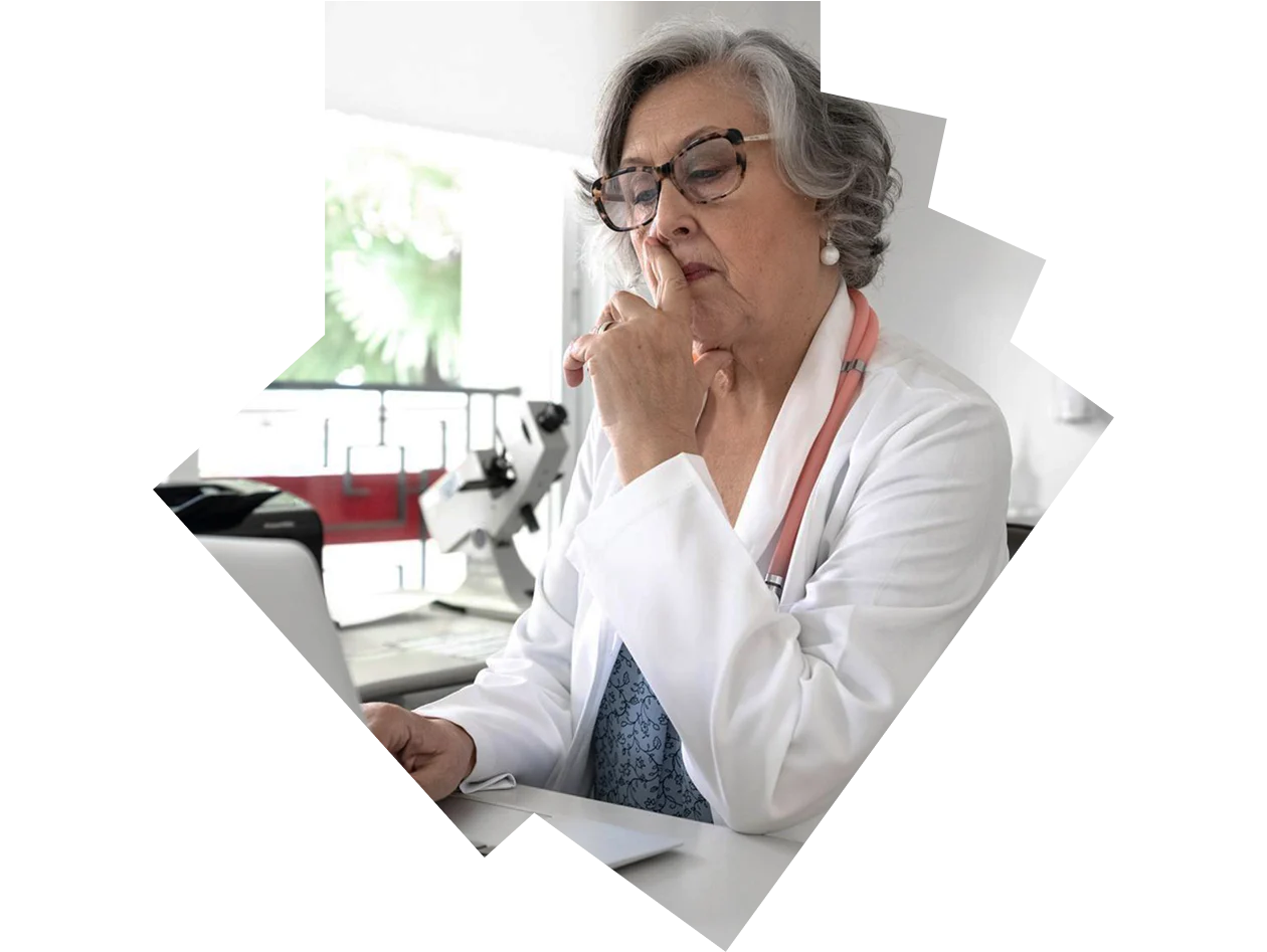 Senior female doctor looking thoughtfully at laptop in her office
