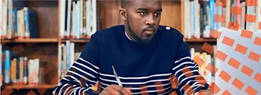 Male author writing notes in a library