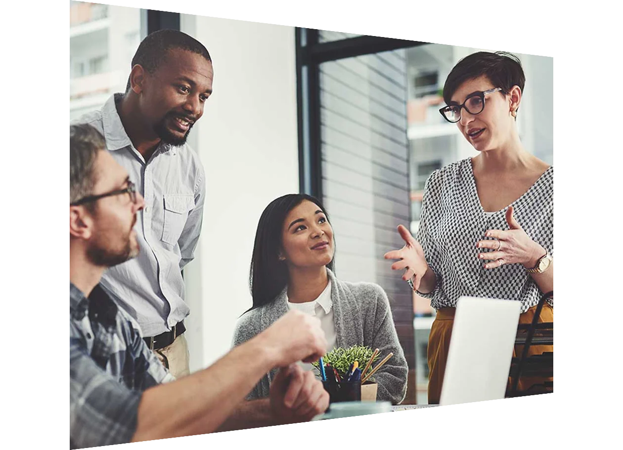 A group of business people gathered around a laptop in their office