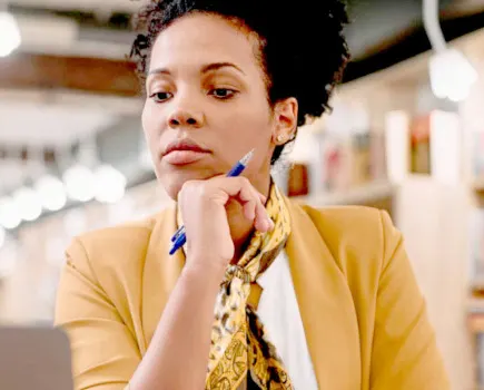 Woman with her fist on her chin looking down at a laptop.