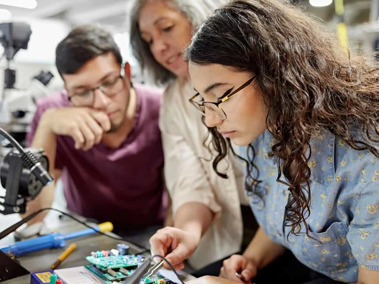 Partnering on solutions for our authors, librarians and institutions. Professor showing students how to build technological device. 