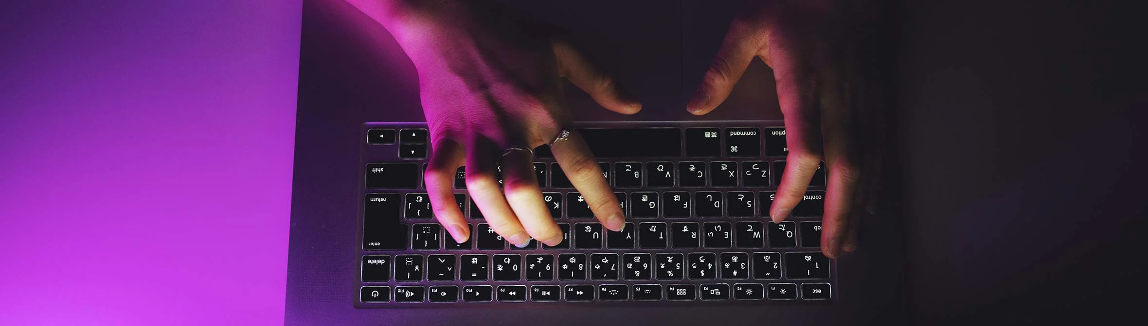 Top view of hands typing on laptop keyboard