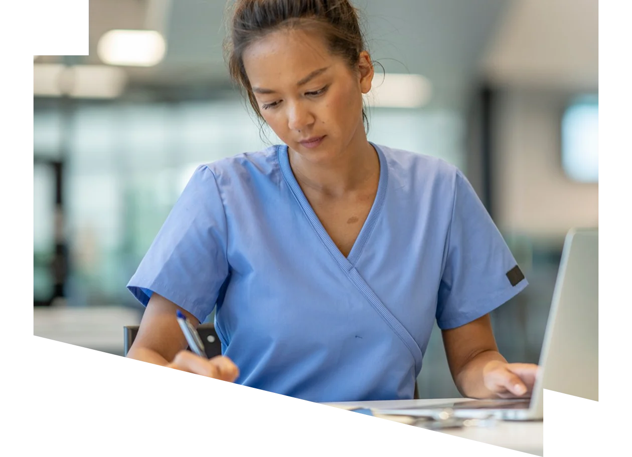 Medical professional wearing scrubs at his desk looking at digital tablet