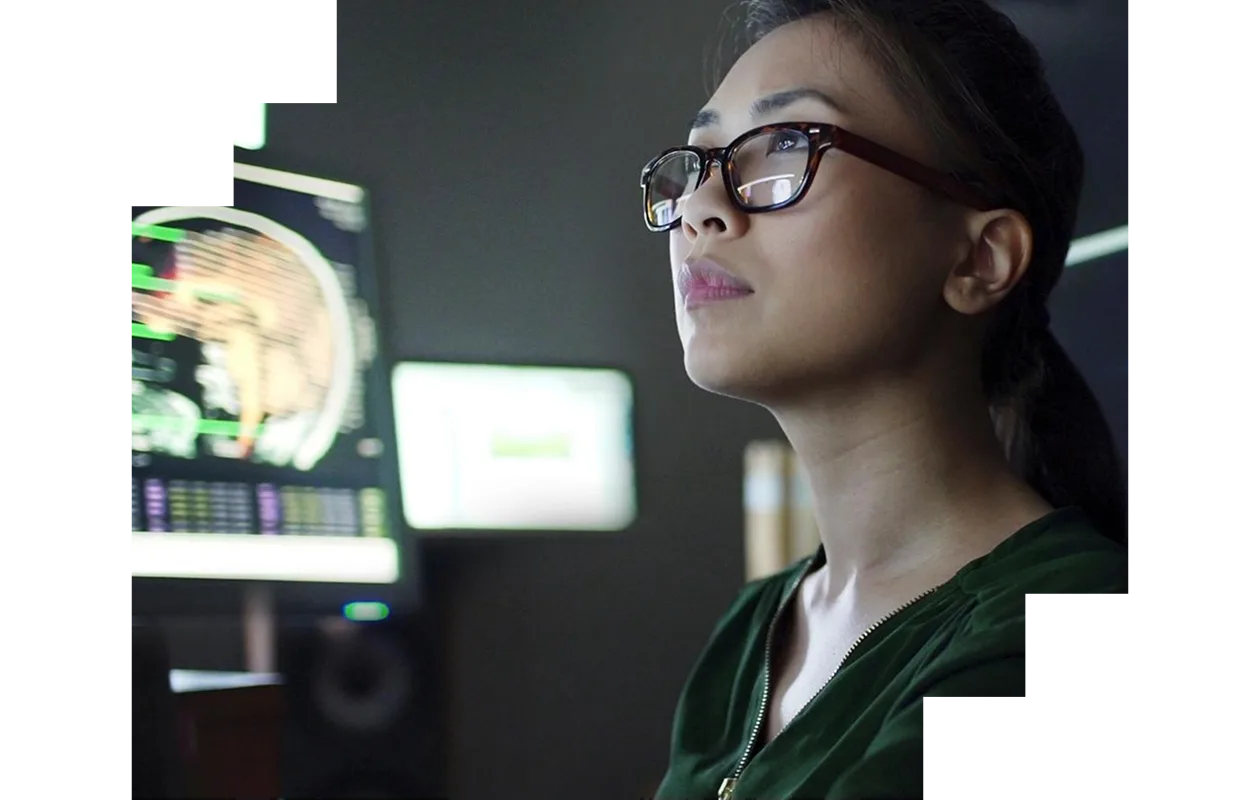A woman in a lab coat is focused on her phone while standing in a laboratory setting.