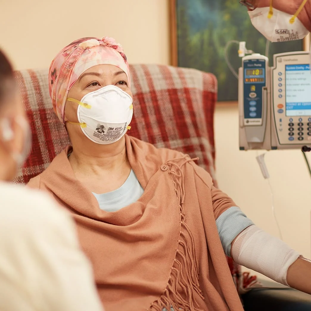 Seated patient in mask with family member and physician