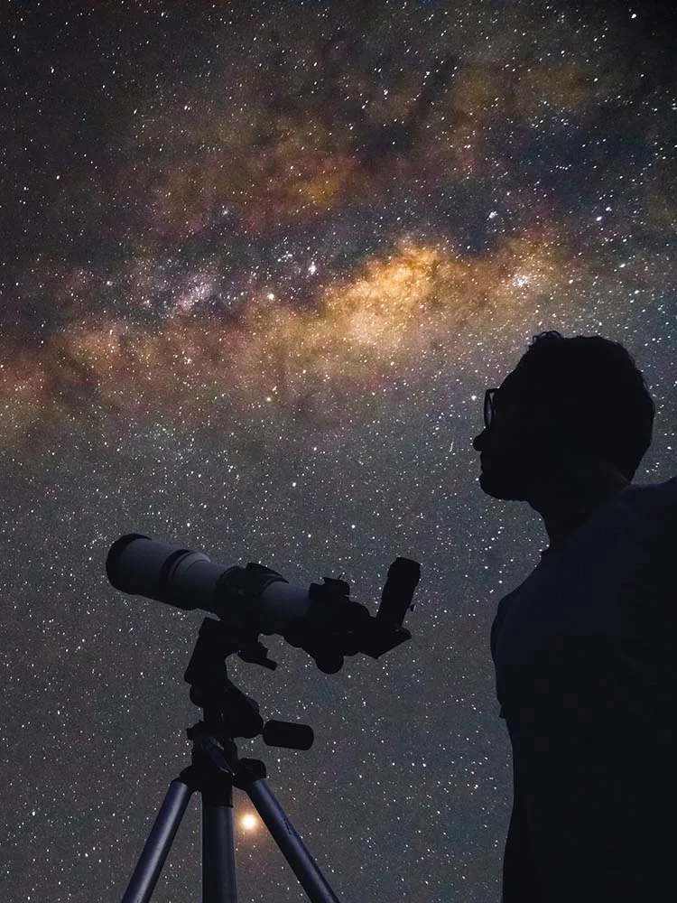man with telescope looking at galaxy