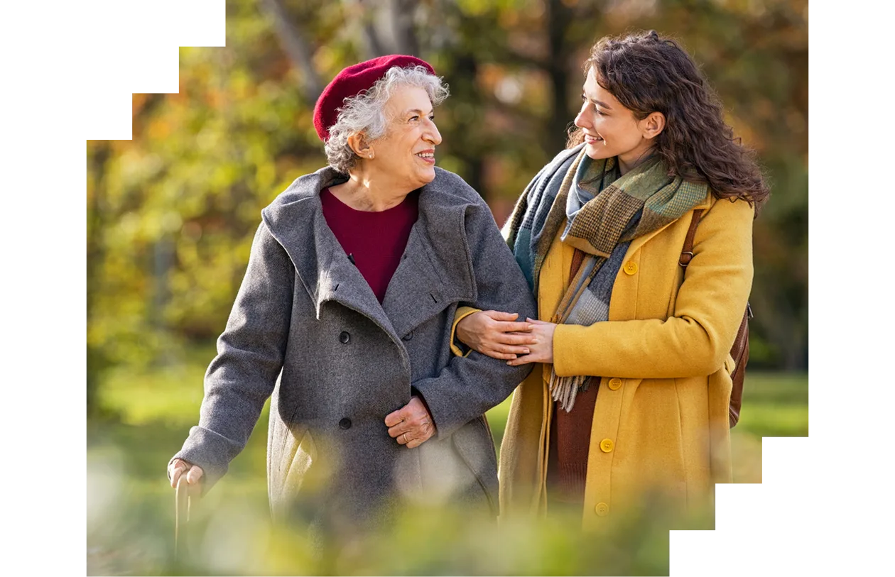 Senior woman walking with granddaughter in park during autumn