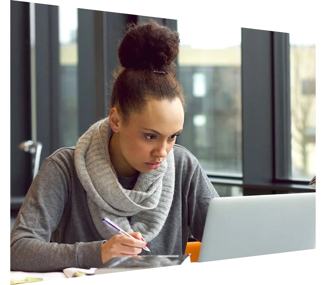 Young woman looking at laptop taking notes