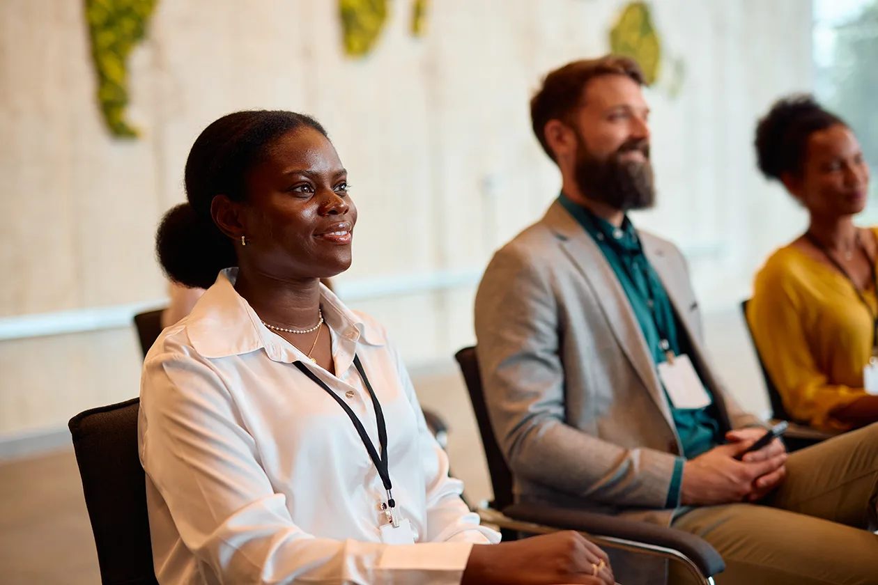 Three people sitting in a row of chairs seemingly excited about what is being proposed. 