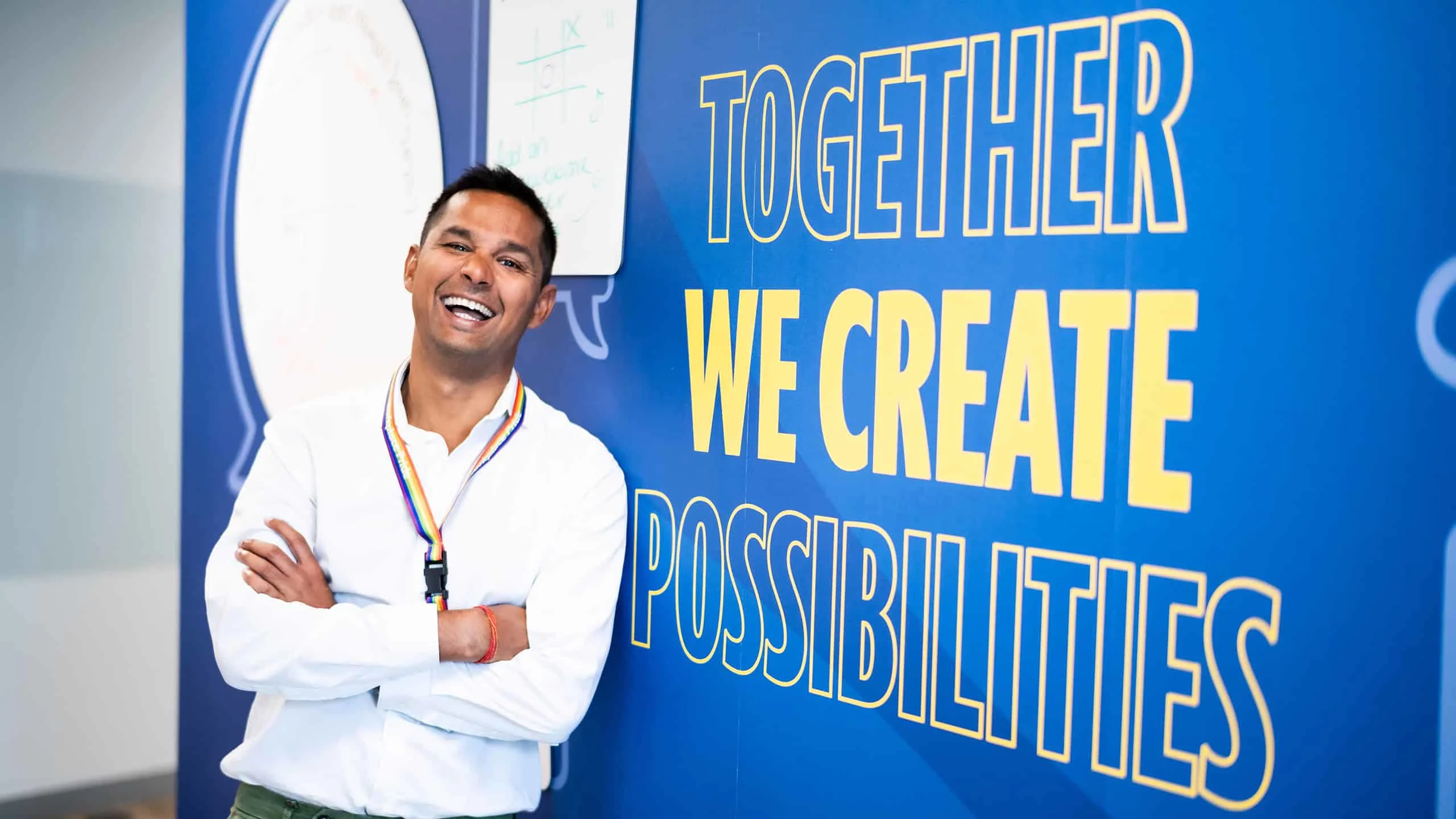 Elsevier employee, standing next to an office wall that says, "Together We Create Possibilities"