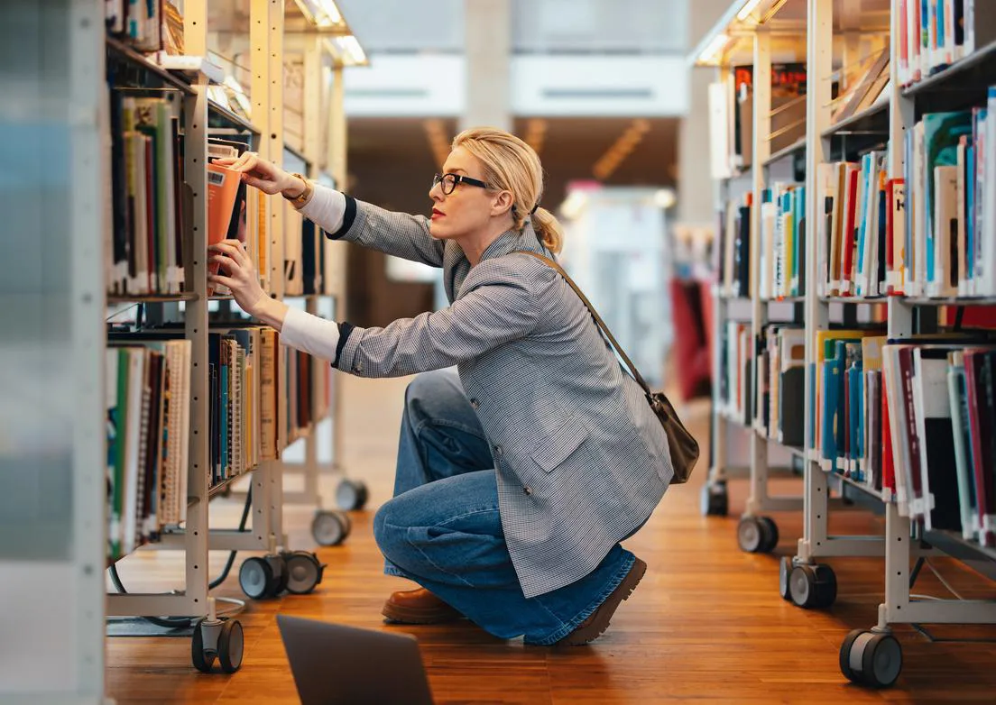 Businesswoman Choosing A New Book In The Library