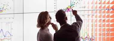 Two men viewing a large screen of information
