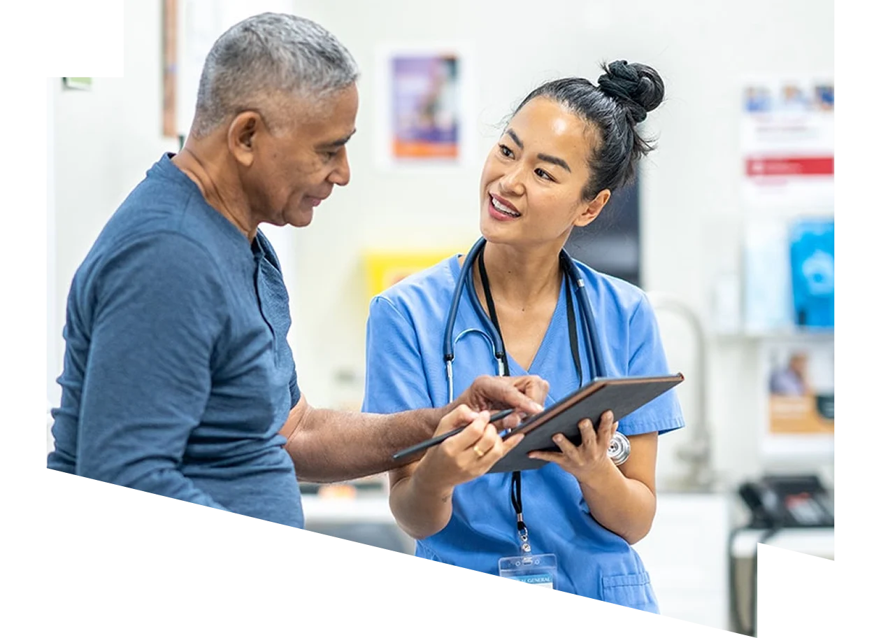 Female clinician reviews information on a tablet with mature male patient.