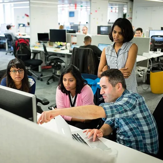 Group of colleagues sitting at a desk looking at a monitor