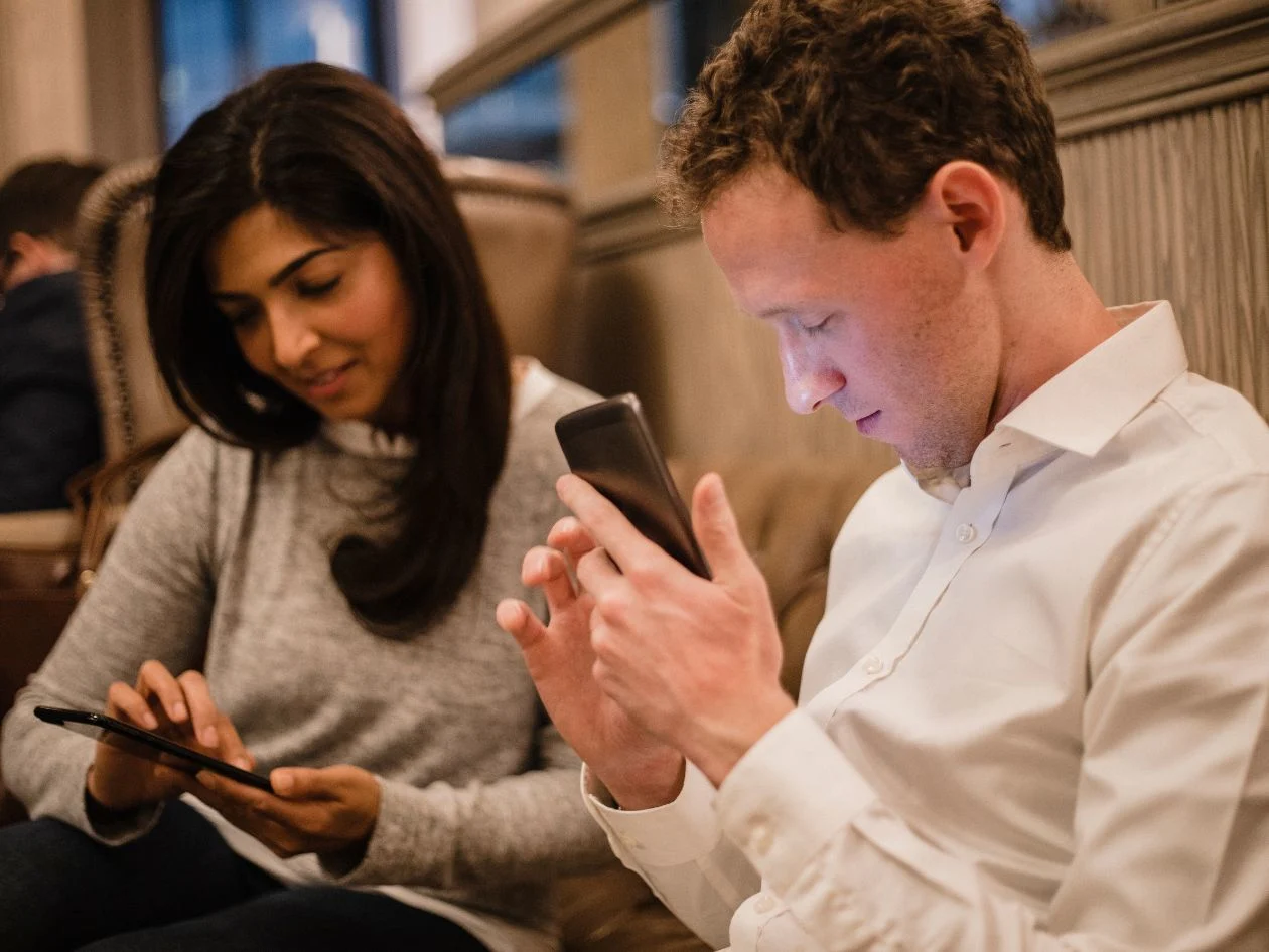 Two people checking their phone