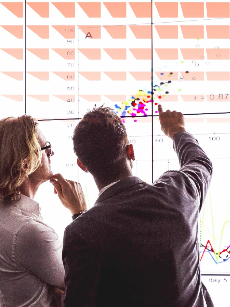 Two men viewing a large screen of information