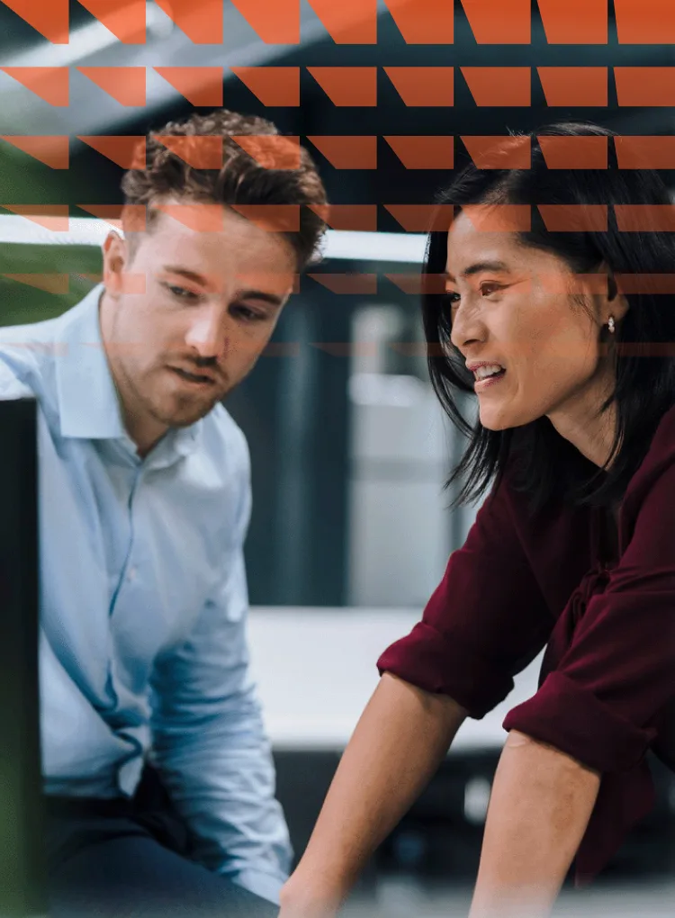 Young businessman discussing with colleague over desktop PC in office