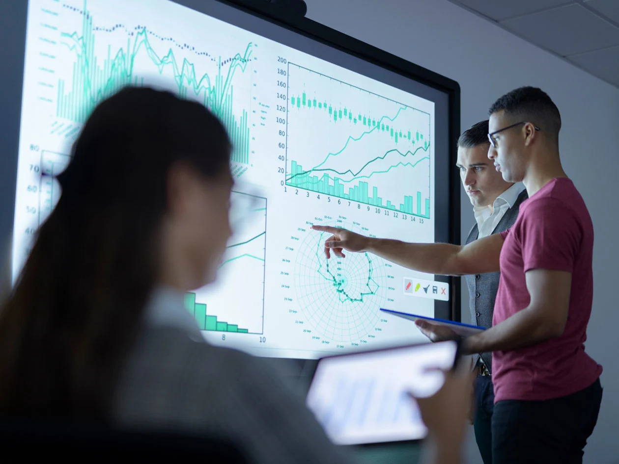 Researchers pointing at large screen with data