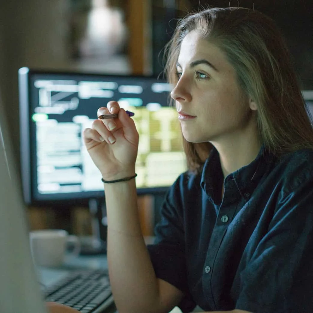 A woman sitting at desk surrounded by monitors