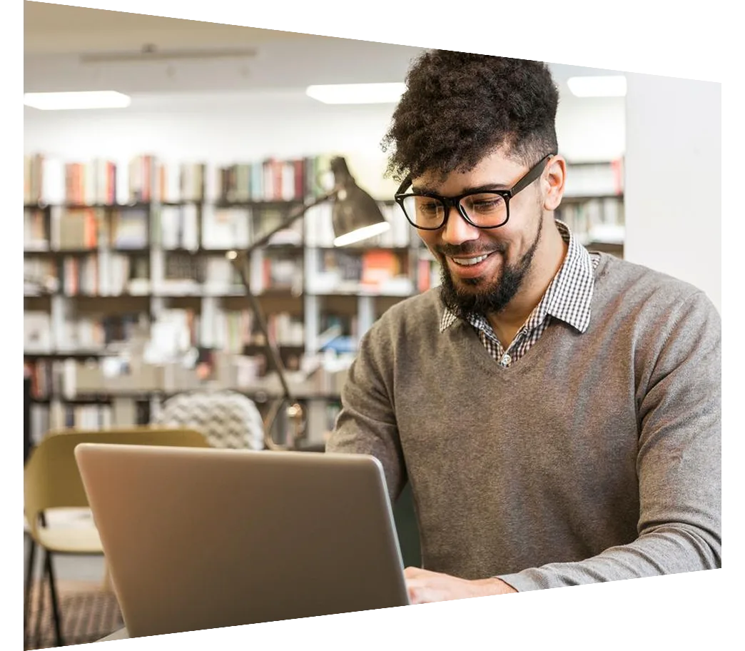 Young man in library on laptop