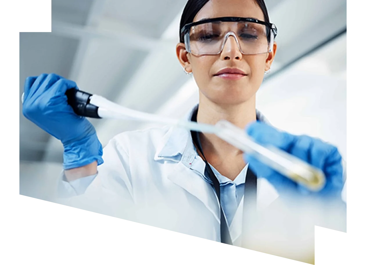 Female scientist wearing safety goggles and gloves pipetting a sample into a testtube