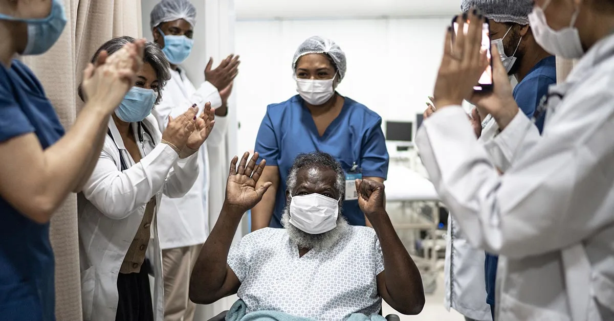 Doctors and nurses celebrating man leaving the hospital after recovery (© istock.com/FG Trade)