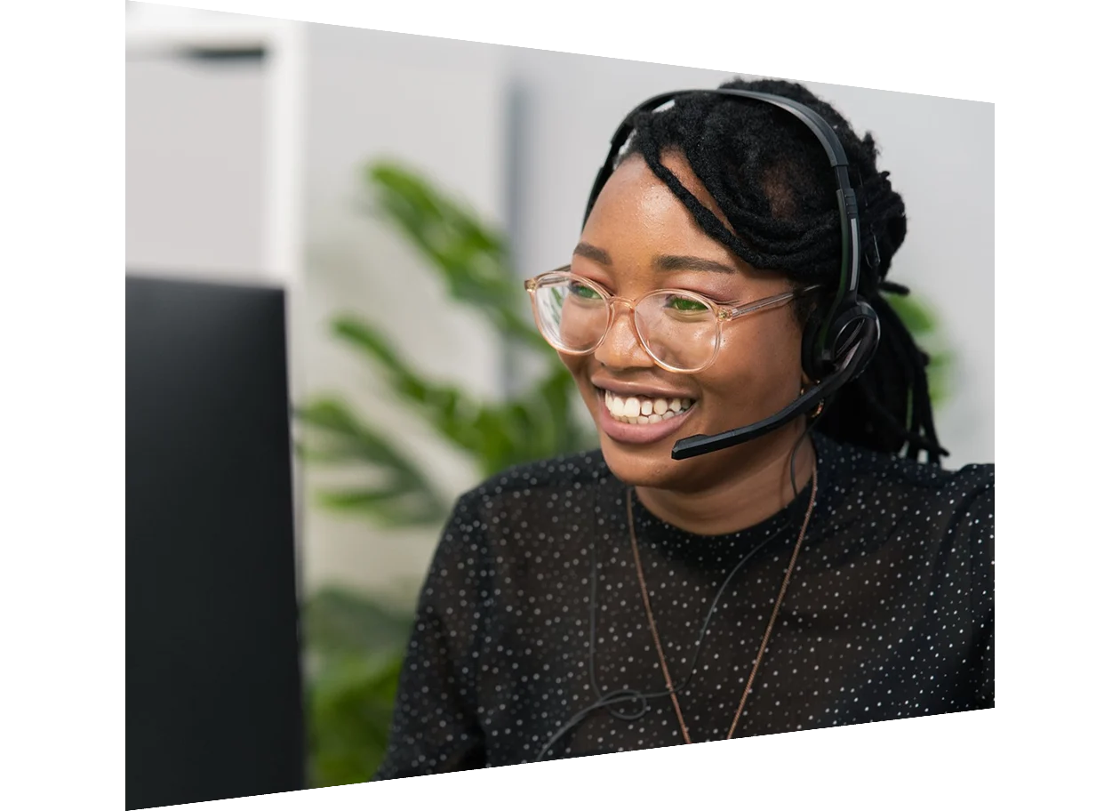 Customer service agent wearing headphones sitting at desk in front of computer screen