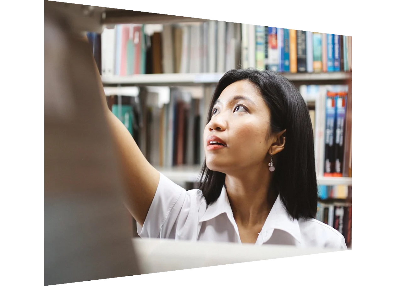 Woman grabbing book from library shelf