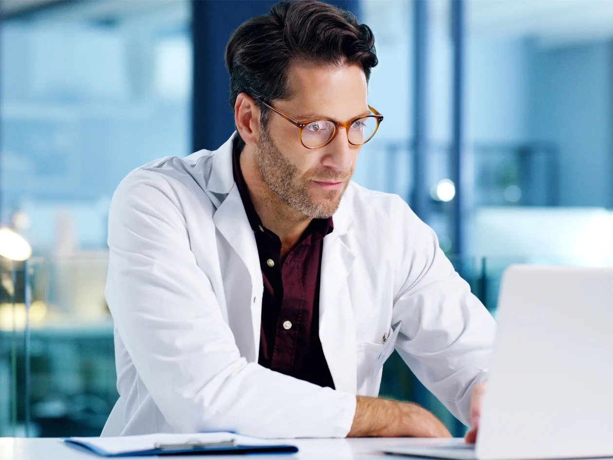 A mature male doctor using a laptop in a hospital