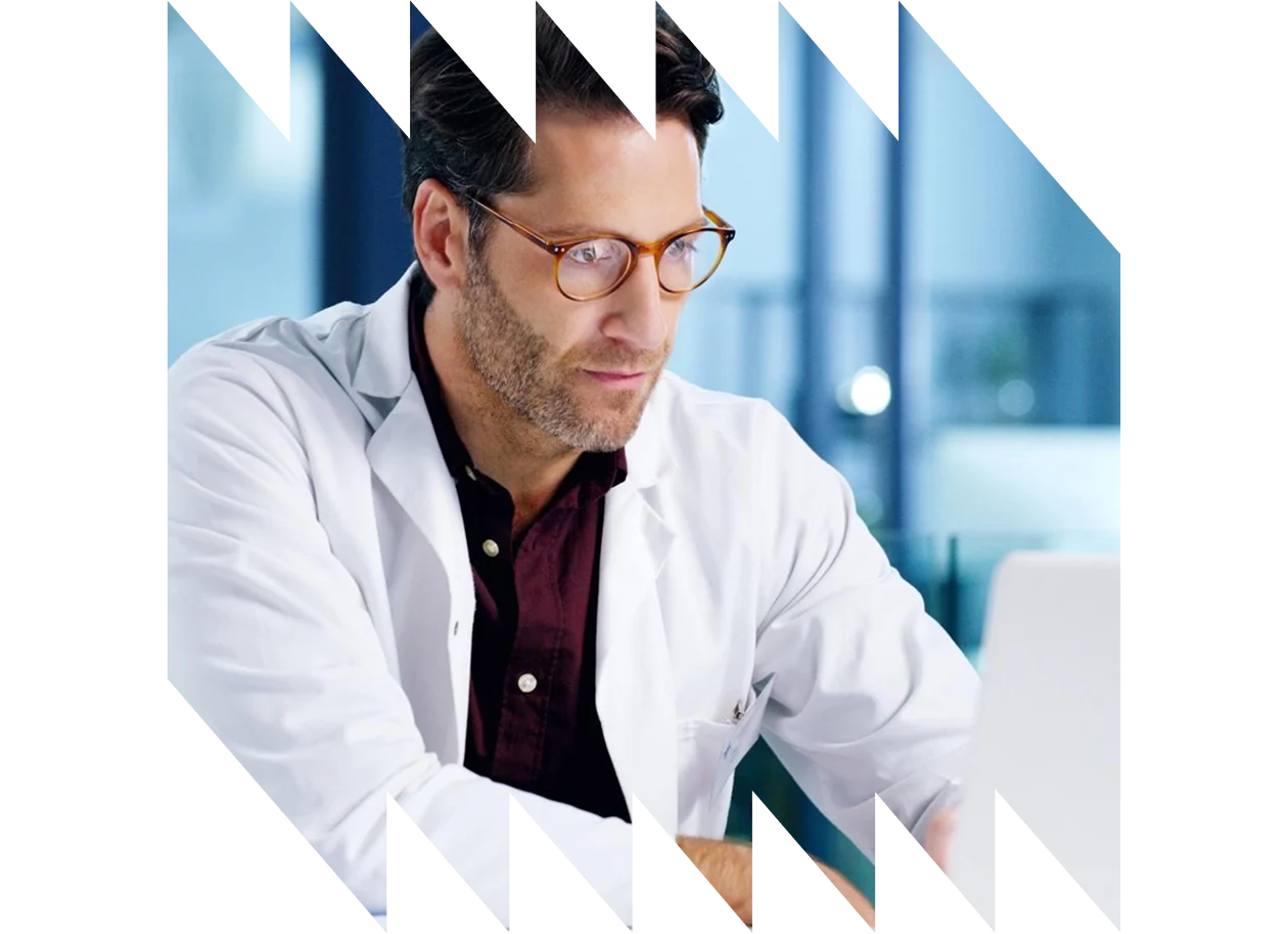 A mature male doctor using a laptop in a hospital